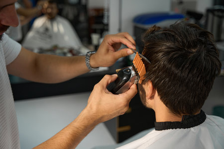 Barber tending to his client hair with portable trimmerの写真素材