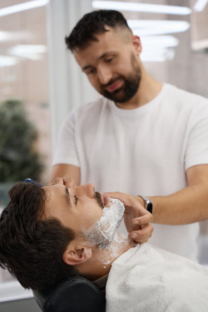 Young brunet man having his face shaved at hair salonの写真素材