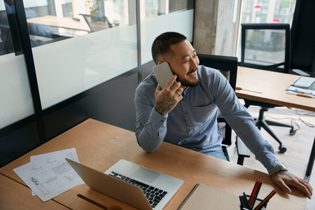 Cheerful male office worker talking on smartphoneの写真素材