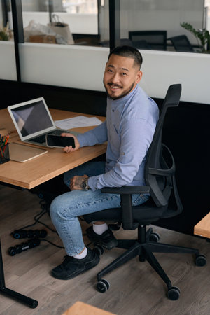 Joyous company employee posing for camera at office desk