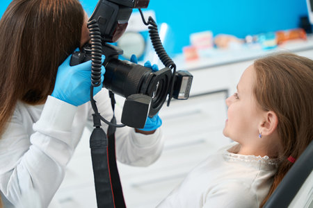 Pedodontist photographing mouth of little patient during consultationの写真素材