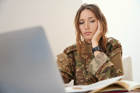 Woman in a camouflage uniform works with working documents and a gadgetの写真素材