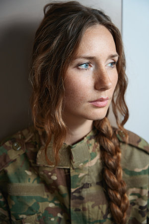 Woman in camouflage uniform looking to right with serious expressionの写真素材