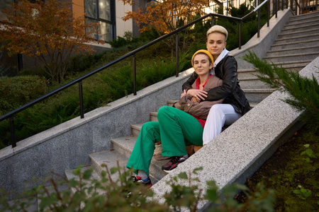 Brunette in beige trench coat in arms of her girlfriendの写真素材