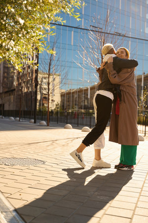 Woman joyfully hugs her girlfriend against the backdropの写真素材