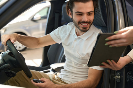 Joyful automotive buyer perusing car purchase agreement on tablet computer