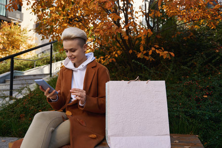 Young woman is resting on bench, she is in correspondence phone