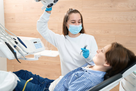 Friendly female dentist encourages a young patient before tooth extractionの写真素材