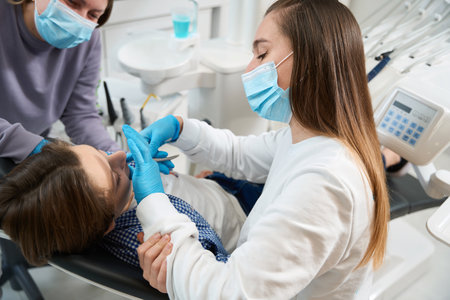 Woman dentist removes a tooth to a young patientの写真素材