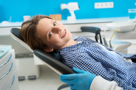 Smiling teenager sits in a dental chair among special equipmentの写真素材