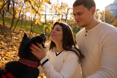 Young cheerful couple walking their dog in the park