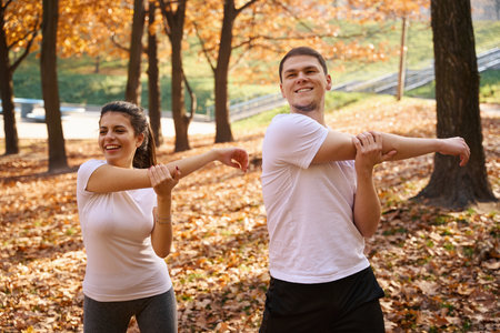 Joyful man and woman doing morning exercises in city parkの写真素材