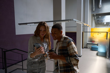 Smiling lady showing mobile phone screen to her male friend