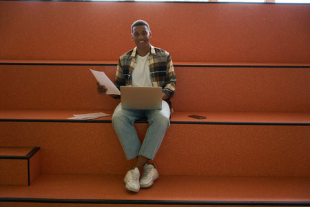 Happy male student using laptop in university