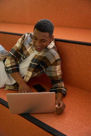 Smiling male student looking at laptop screen