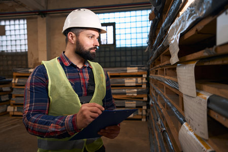 Portrait of man making notes in warehouseの写真素材