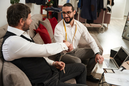 Contented fashion designer greeting his business partner in atelierの写真素材