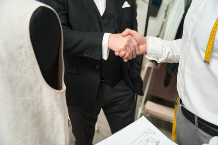 Gentleman exchanging handshake with fashion designer indoorsの写真素材