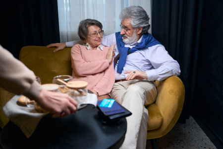Cute mature couple is chatting in the hotel recreation areaの写真素材