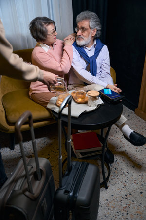 Traveling elderly couple resting from the road in hotel cafeの写真素材