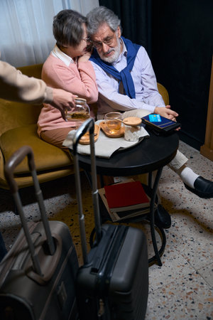 Modern grandparents are resting from the road in hotel cafeの写真素材