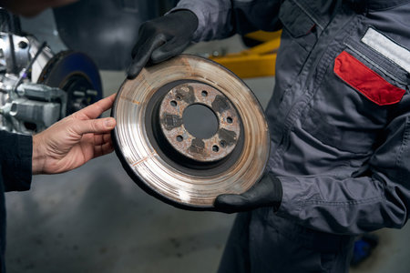 Man holding brake disc, talking with clientの写真素材