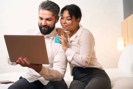 Joyous couple making online payment in hotel roomの写真素材
