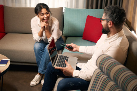 Mixed-race tourist couple whiling away time in hotel foyer