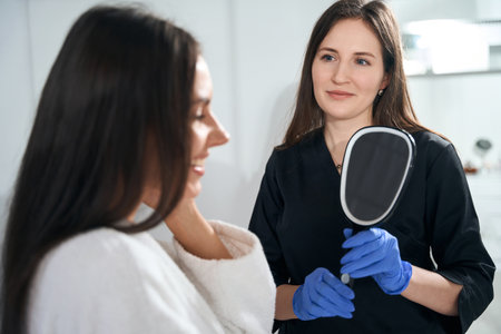 Young lady standing near cosmetologist in protective suitの写真素材