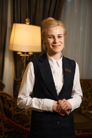 Pretty female hotel manager stands in room with luxurious interiorの写真素材