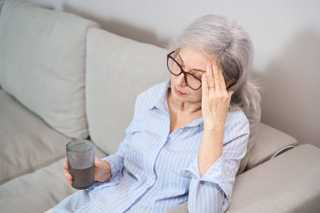 Gray-haired grandmother suffers from a headache at homeの写真素材
