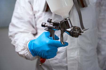 Man in protective gloves holdsaerosol spray gun for painting carの写真素材