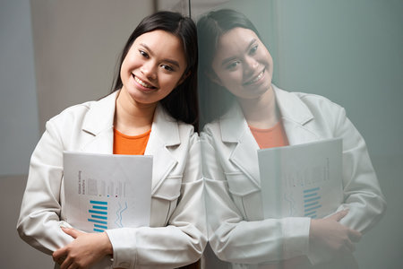 Joyful female office worker with business documentation posing for cameraの写真素材