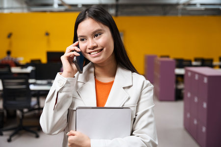 Smiling corporate worker talking on cellphone in open-plan office