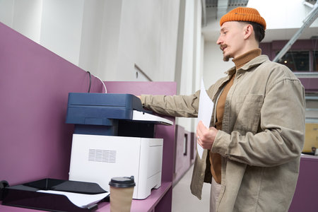 Focused company employee making photocopies on copierの写真素材