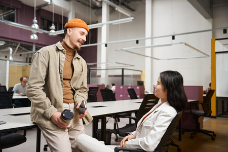 Smiling company employee communicating with female colleague during coffee break