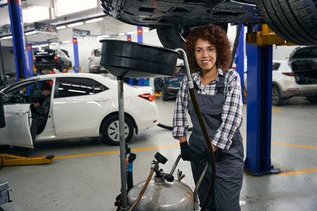 Young auto repair worker with special reservoir for draining brake fluidの写真素材