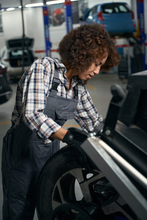 Woman in a car repair shop works with car wheelの写真素材