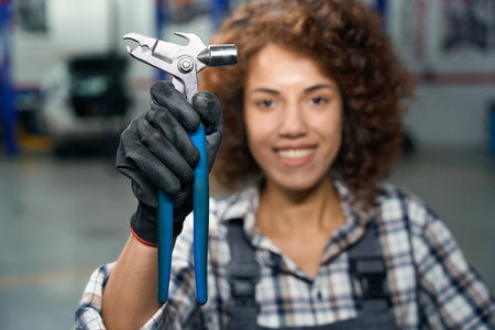 Smiling curly multiracial woman holding adjustable wrenchの写真素材