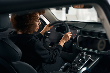 Smiling multiracial female shopper sits behind the wheelの写真素材