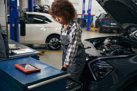Young auto repair worker in plaid shirt stands near carの写真素材