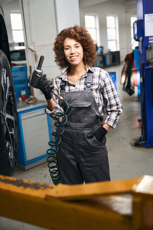 Happy young woman holding a pneumatic screwdriver in her handsの写真素材