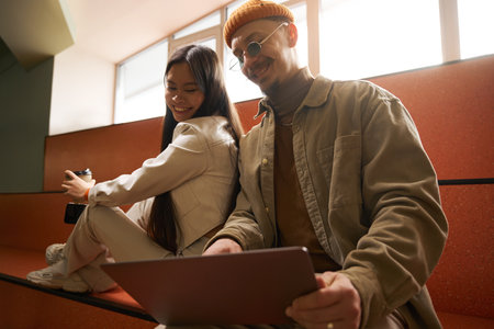 Joyful couple watching something on portable computerの写真素材