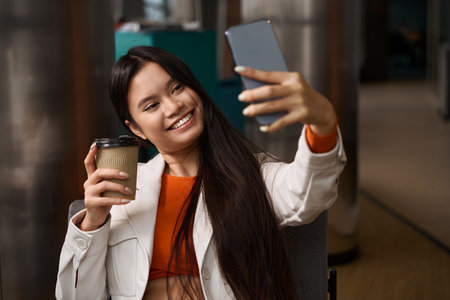 Cheerful female office worker taking selfie during coffee breakの写真素材