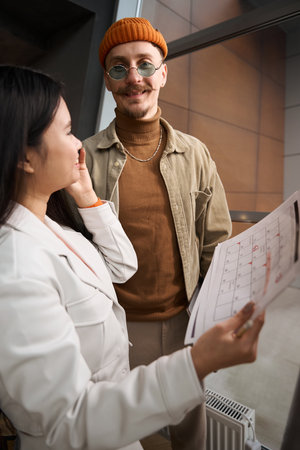Corporate employee standing beside her coworker during phone conversationの写真素材