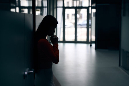 Sad corporate worker standing in dark empty office corridorの写真素材