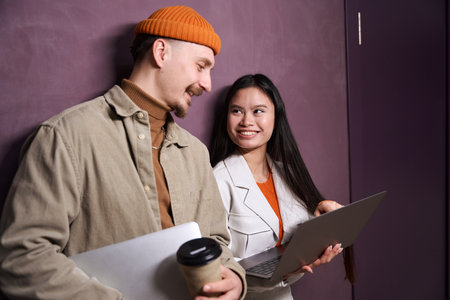 Mixed-race couple with portable computers communicating by wallの写真素材