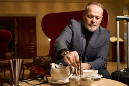 Gray-haired male drinking tea in a recreation areaの写真素材