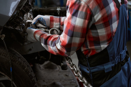 Worker attaches a carabiner with chain to the car bodyの写真素材