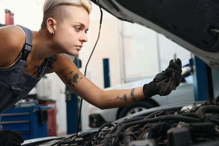 Concentrated female worker servicing car in vehicle detailing workshopの写真素材
